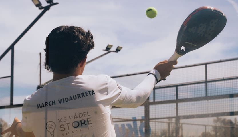 Padel player swinging at an outdoor court